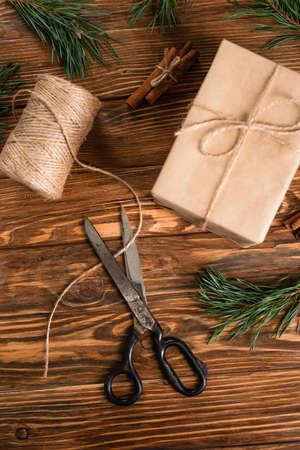 top view of wrapped gift box near scissors on wooden surfaceの写真素材