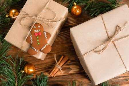 top view of gingerbread cookie on gift box near blurred pine branches and cinnamon sticks on wooden surfaceの写真素材