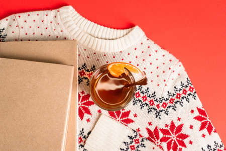 top view of books and cup of tea on knitted sweater on red