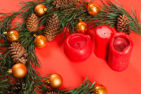 high angle view of pine cones near green branches with christmas balls and candles on redの写真素材