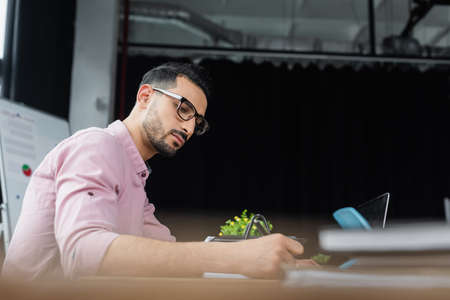 Muslim businessman in eyeglasses working near laptop in office