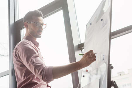 Low angle view of muslim businessman writing on flip chart in officeの写真素材