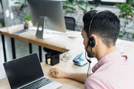 Arabian businessman using headset during video chat on laptop in officeの写真素材