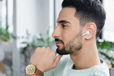 Side view of muslim businessman in wireless earphone in office