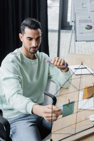 Young arabian businessman looking at blurred sticky notes in office