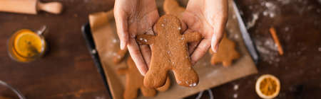 Top view of african american woman holding christmas gingerbread near blurred tray in kitchen,...