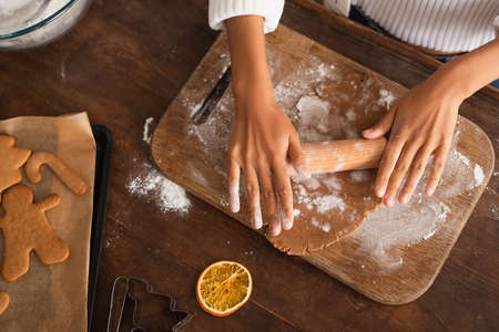 Cropped view of african american woman rolling dough near dry orange slice and christmas cookies in kitchenの写真素材