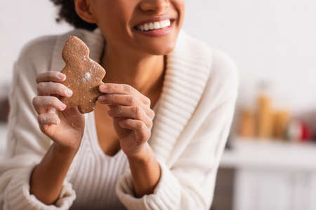 Cropped view of african american woman with flour on hands holding christmas cookieの写真素材