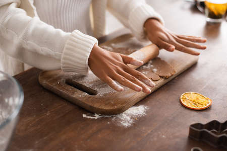 Cropped view of african american woman rolling dough near cookie cutter in kitchen