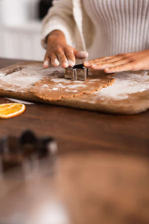 Cropped view of african american woman holding cookie cutter on dough near dry orange slice in kitchenの写真素材