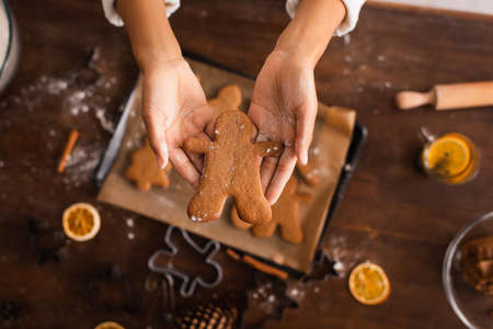 Cropped view of african american woman holding christmas cookie near blurred tray in kitchen
