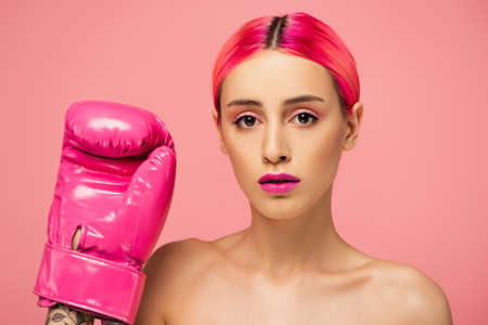 young woman with dyed hair and bright makeup in boxing glove isolated on pinkの写真素材