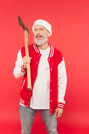 middle aged man in santa hat holding axe on redの写真素材
