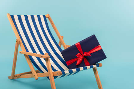 present on striped deck chair on blue background