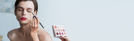 makeup artist applying eye shadow on transgender man, bannerの写真素材