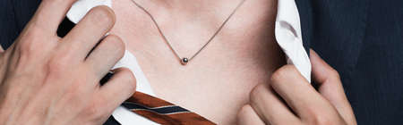 cropped view of transsexual man adjusting shirt and showing silver necklace, banner