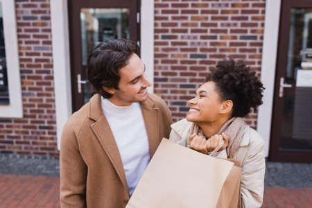 happy man looking at pleased african american woman with shopping bagsの写真素材