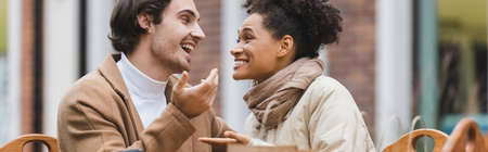 cheerful interracial couple talking and looking at each other, bannerの写真素材