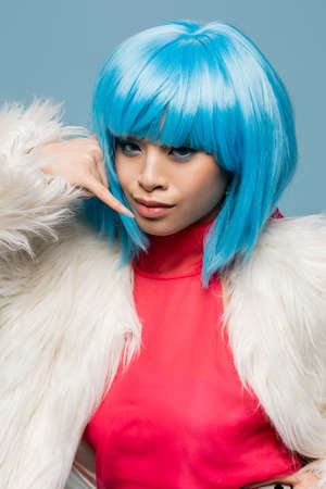 Pretty asian woman in pop art style showing call gesture isolated on blueの写真素材