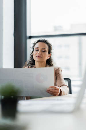 african american businesswoman working with document in office on blurred foregroundの写真素材