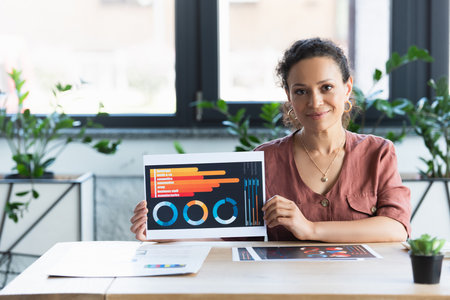 African american businesswoman showing paper with charts in office