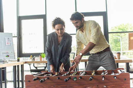 Businessman pointing at table football near african american colleague in officeの写真素材