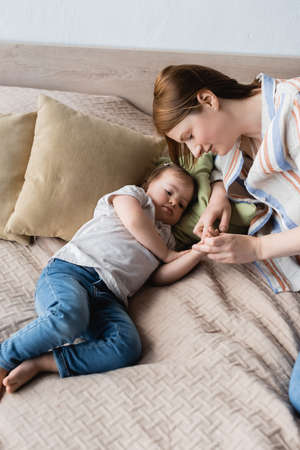 High angle view of woman and child with down syndrome holding hands on bedの写真素材