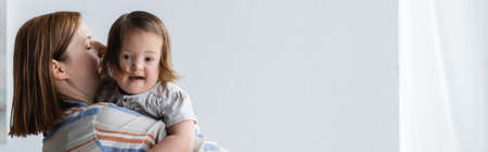 Woman holding toddler daughter with down syndrome at home, bannerの写真素材