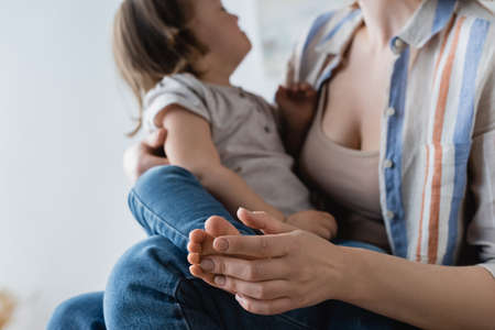 Blurred woman touching leg of daughter with down syndrome at homeの写真素材