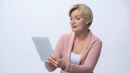 positive middle aged woman using digital tablet isolated on whiteの写真素材