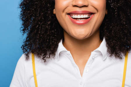 close up view of cropped african american woman smiling isolated on blueの写真素材