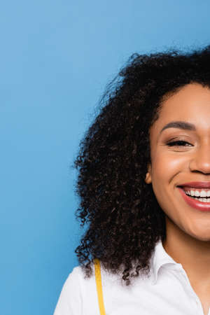 cropped view of happy african american woman smiling at camera isolated on blueの写真素材