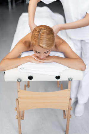masseur doing back massage to blonde client with closed eyesの写真素材
