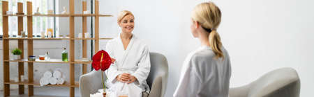 happy woman in bathrobe looking at blurred spa specialist, bannerの写真素材