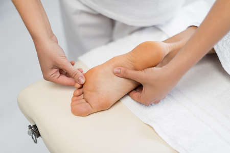 high angle view of professional masseur doing foot massage to client in spa centerの写真素材