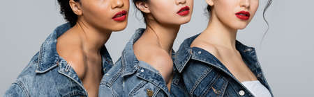Cropped view of interracial women in denim jackets isolated on grey, banner