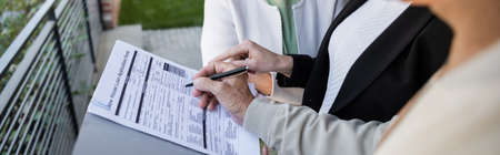 cropped view of blurred man signing loan application near wife and realtor, banner