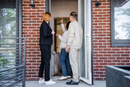 african american woman pointing up in new house near realtor and husbandの写真素材