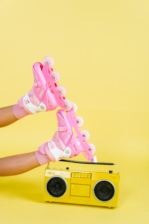 partial view of african american woman on roller skates near retro boombox on yellow