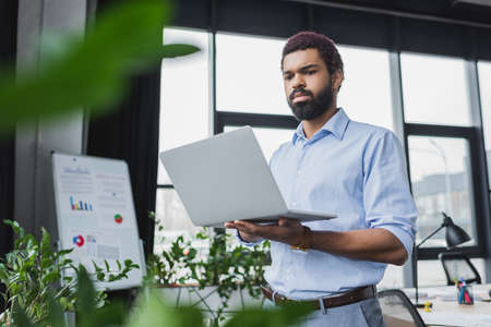 Young african american businessman in formal wear using laptop in office