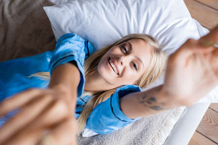 top view of happy and tattooed woman lying on pillow in bedroomの写真素材