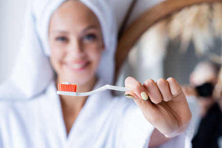 blurred and cheerful woman holding toothbrush with toothpasteの写真素材
