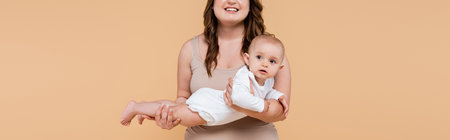 Smiling woman holding baby girl isolated on beige, banner