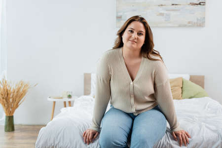 Smiling woman with overweight sitting on bed at homeの写真素材