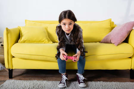 KYIV, UKRAINE - SEPTEMBER 17, 2021: tensed preteen girl playing video game at homeの写真素材