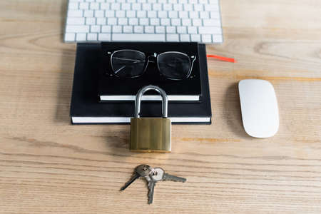 High angle view of padlock with keys near notebooks and computers mouse in officeの写真素材