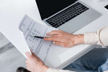 Cropped view of woman counting bills near laptop at homeの写真素材