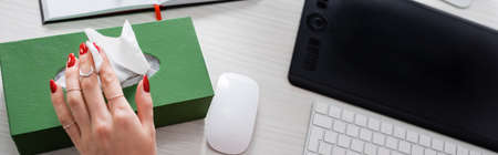 cropped view of sick woman taking paper napkin near graphic tablet, computer mouse and keyboard on desk, bannerの写真素材
