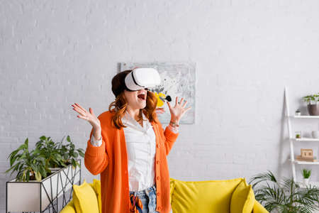 astonished woman in vr headset showing wow gesture while gaming in living room