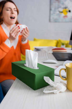 selective focus of pack with paper napkins near sick woman sneezing on blurred backgroundの写真素材